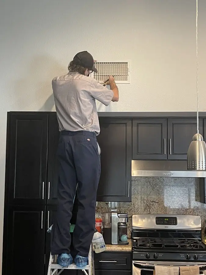 Technician inspecting an air vent during HVAC service in Metropolis